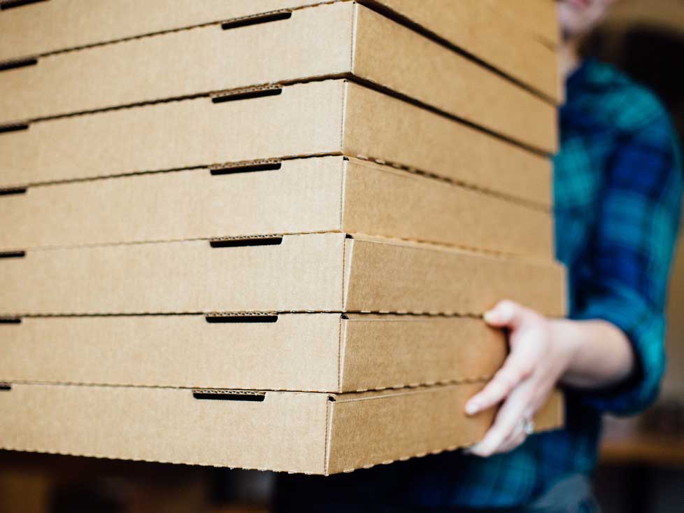 Worker carrying a stack of pizza boxes